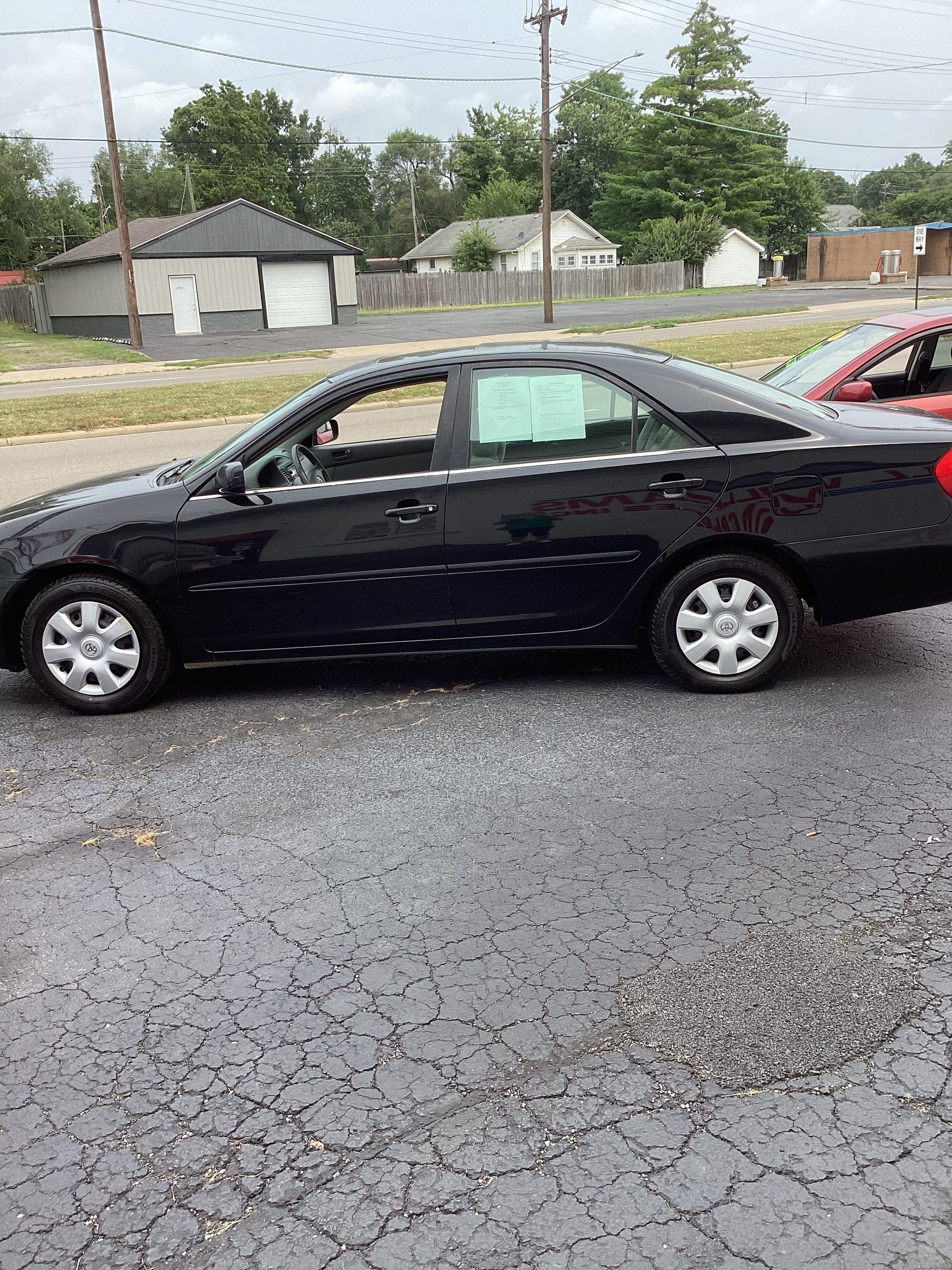 Silver sedan parked on a wet lot in front of a white building