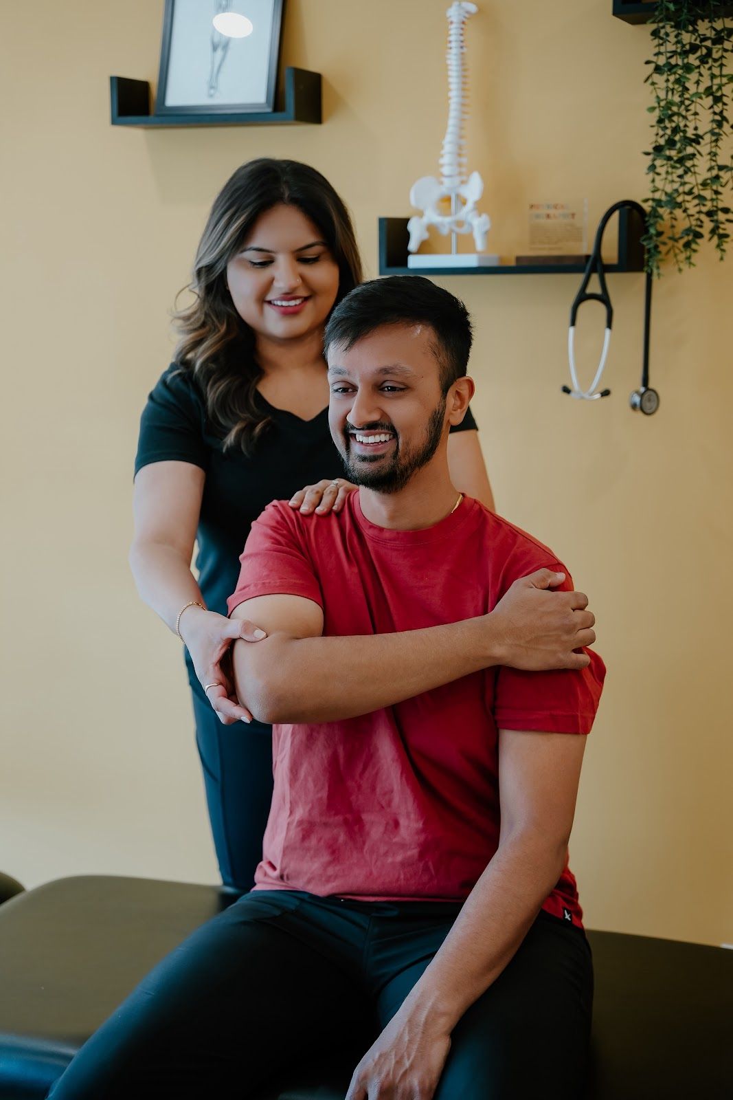A healthcare professional assists a patient with shoulder movement in a clinic.