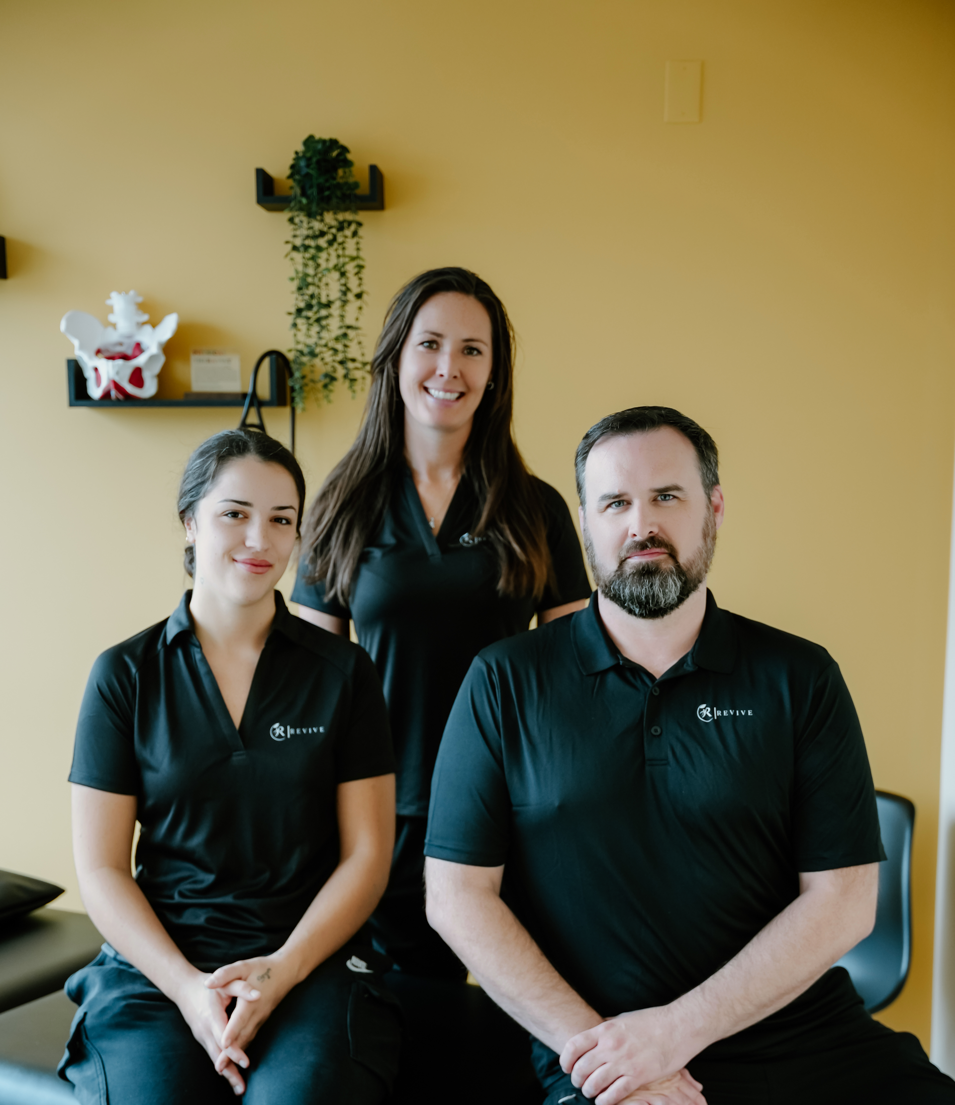 Three healthcare professionals in black shirts smiling in an office setting.