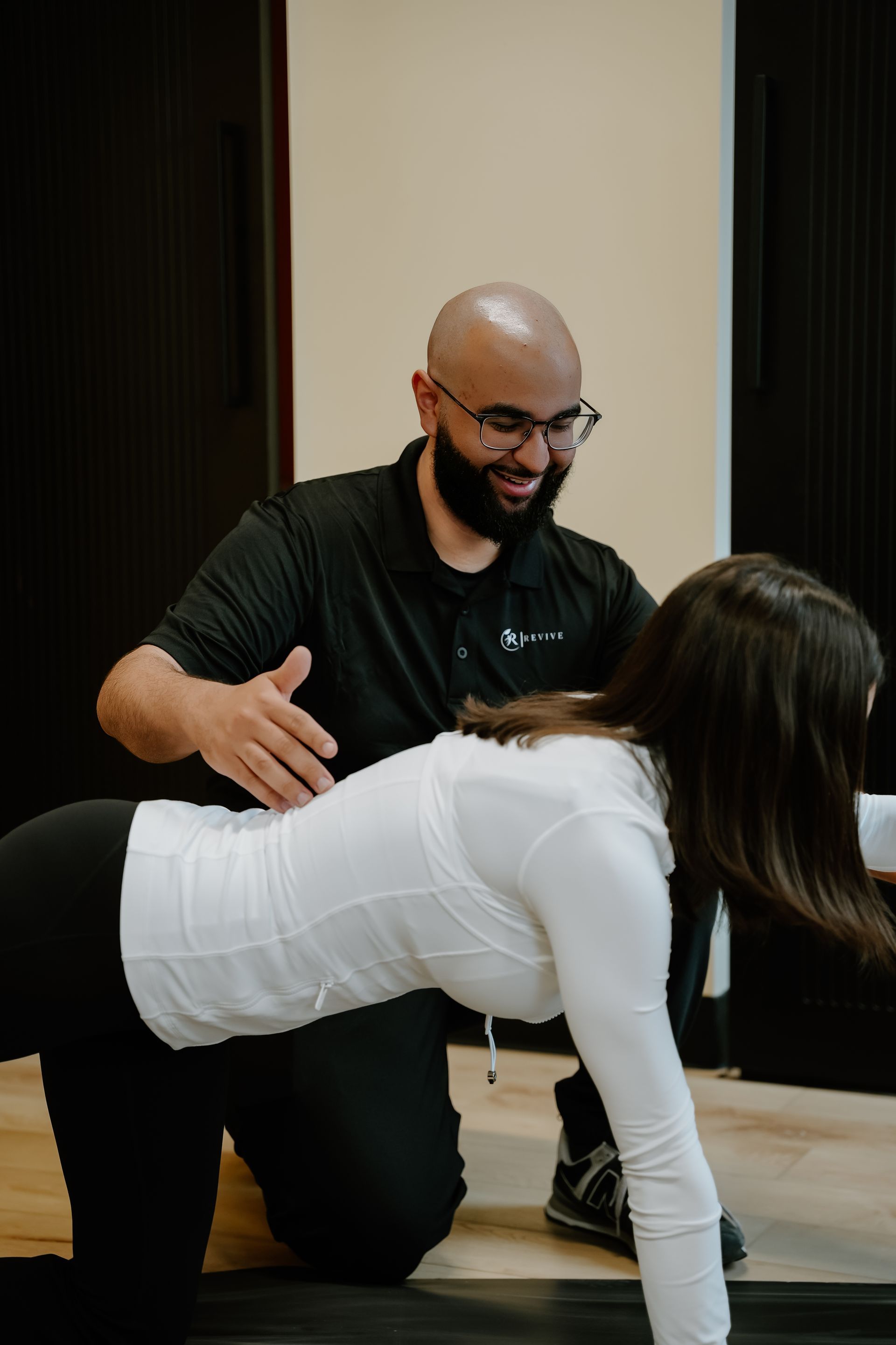Physical therapist guiding a person doing a tabletop exercise indoors. Both smiling.