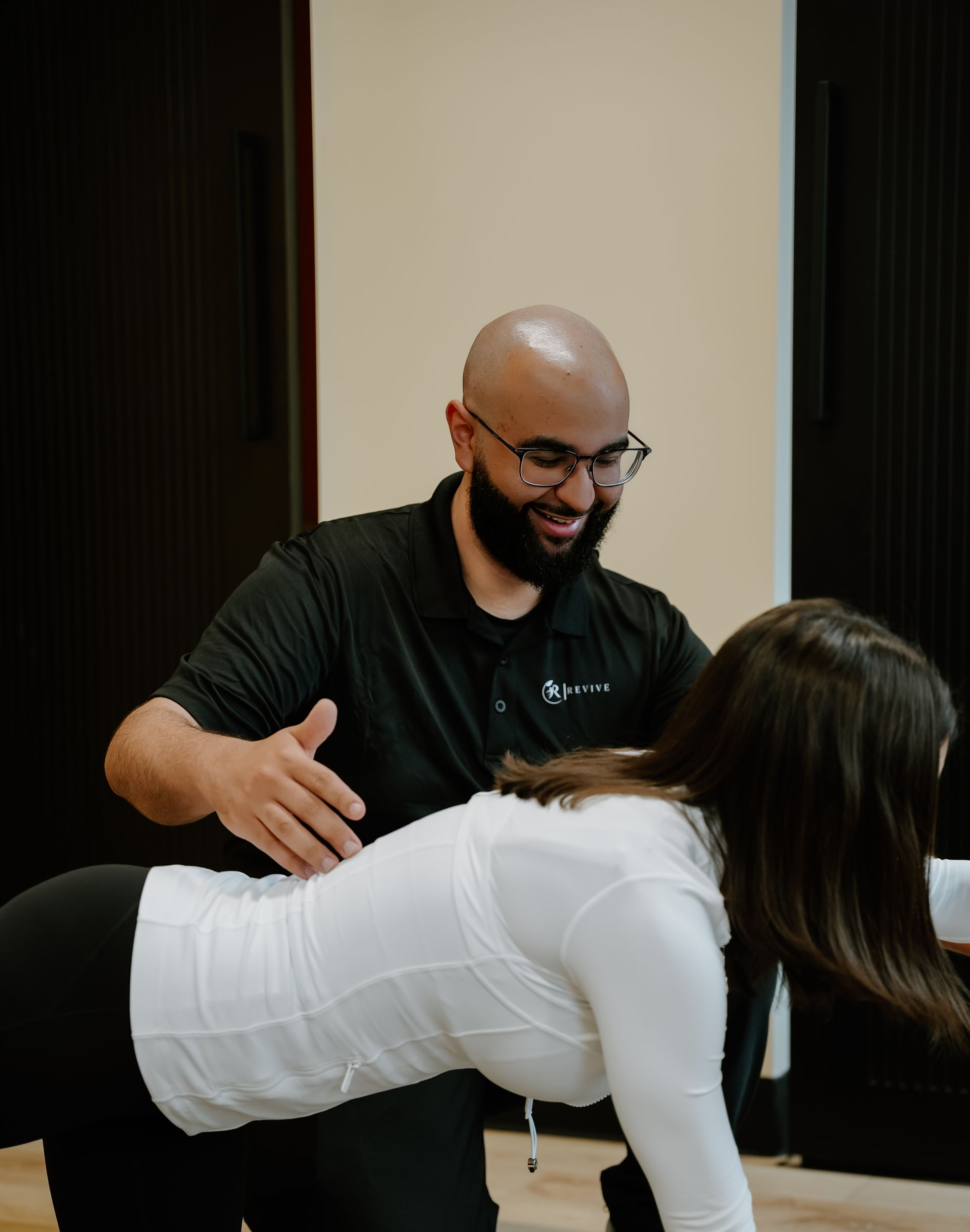 Physical therapist guiding a person doing a tabletop exercise indoors. Both smiling.