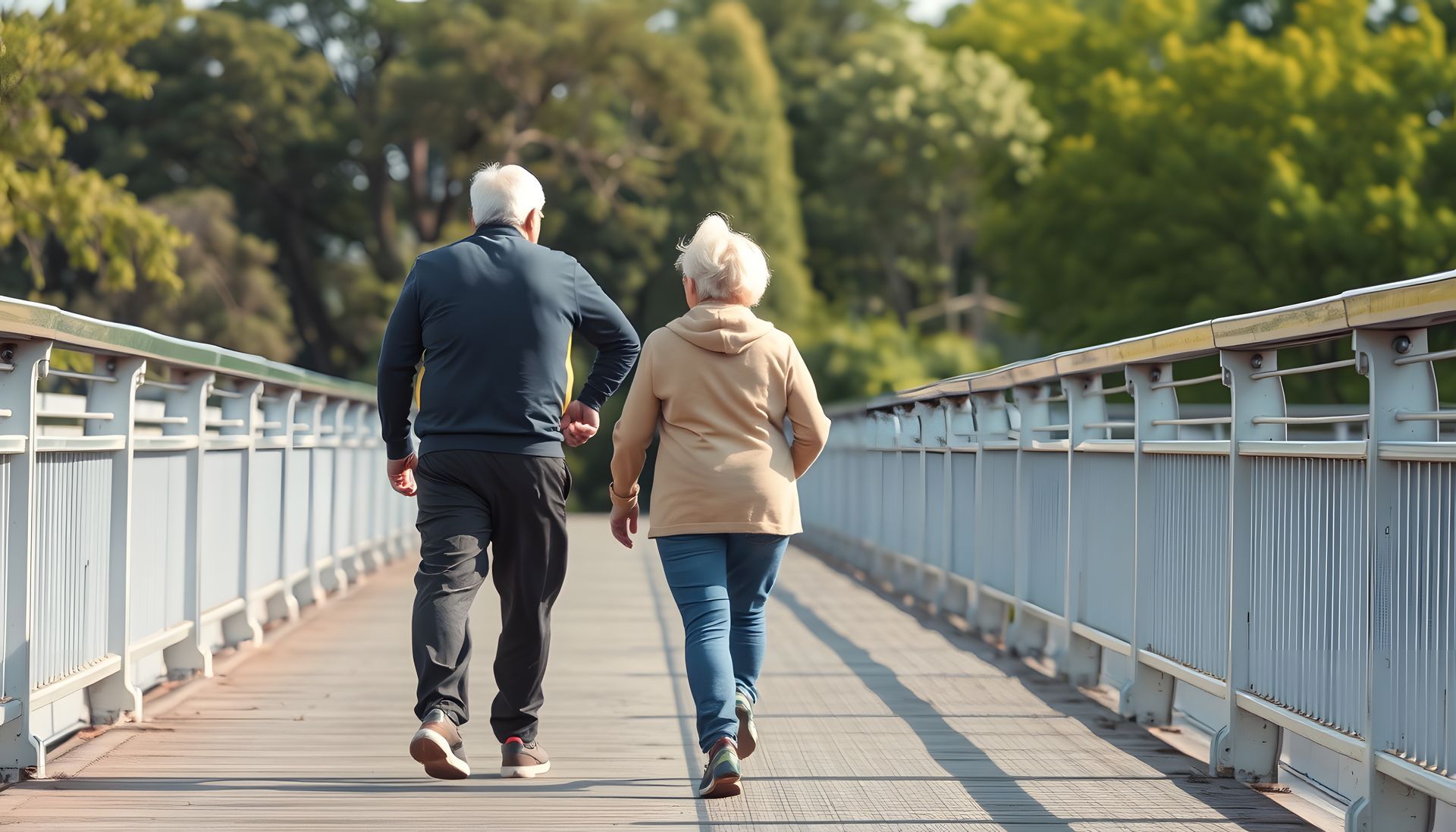 Older couple walks on a bridge, holding hands; sunny outdoor setting.