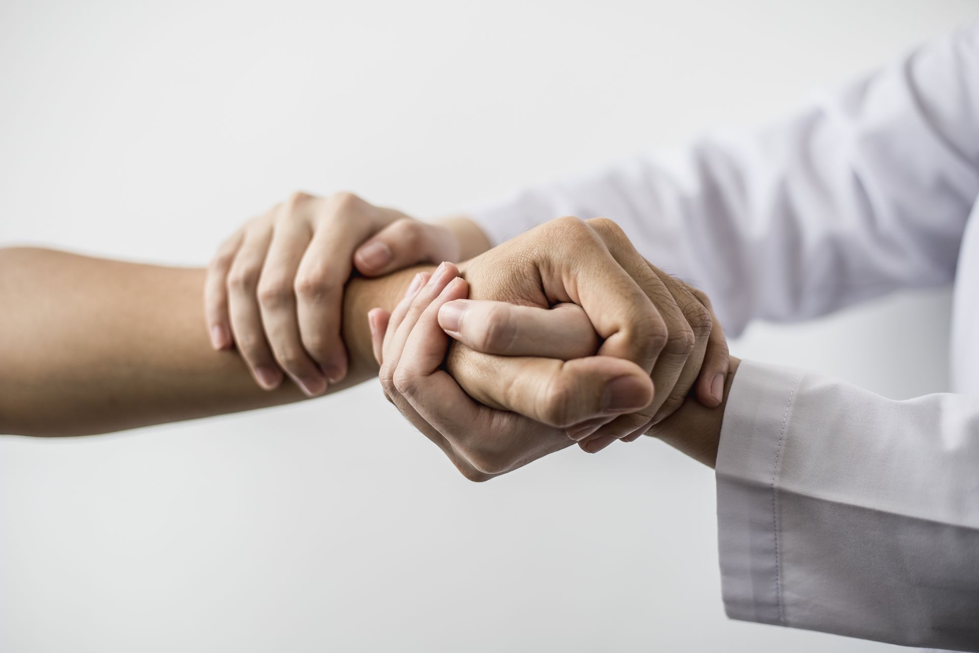 Doctor holding patient's wrist, wearing a white coat.