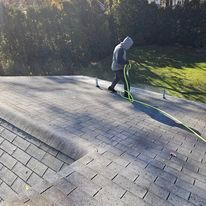 A man is cleaning a roof with a hose.