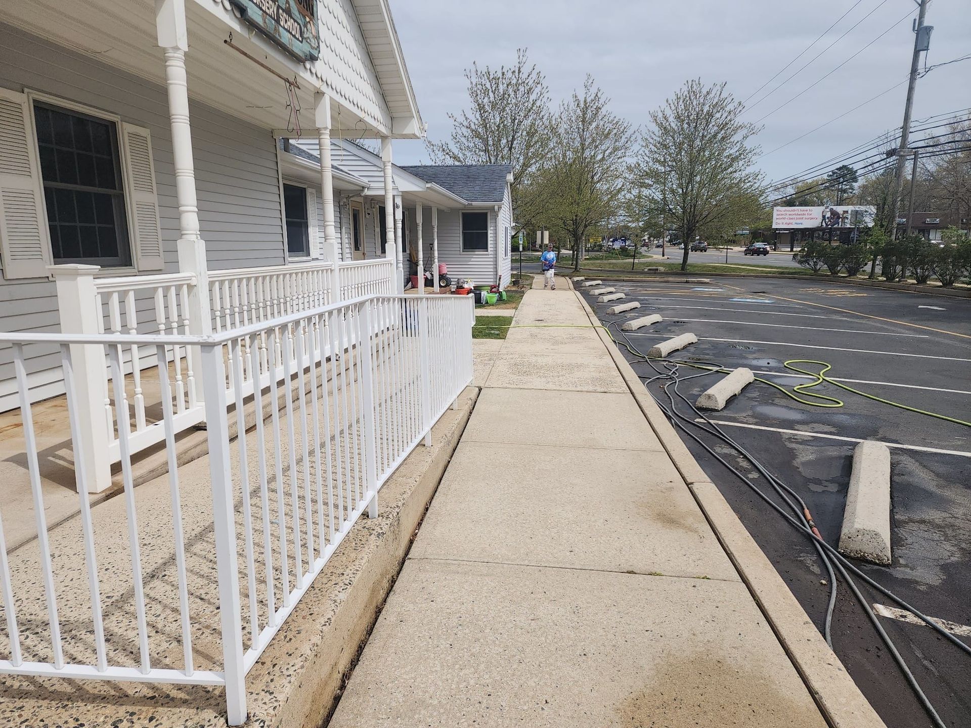 A clean sidewalk with a white railing leading to a house.