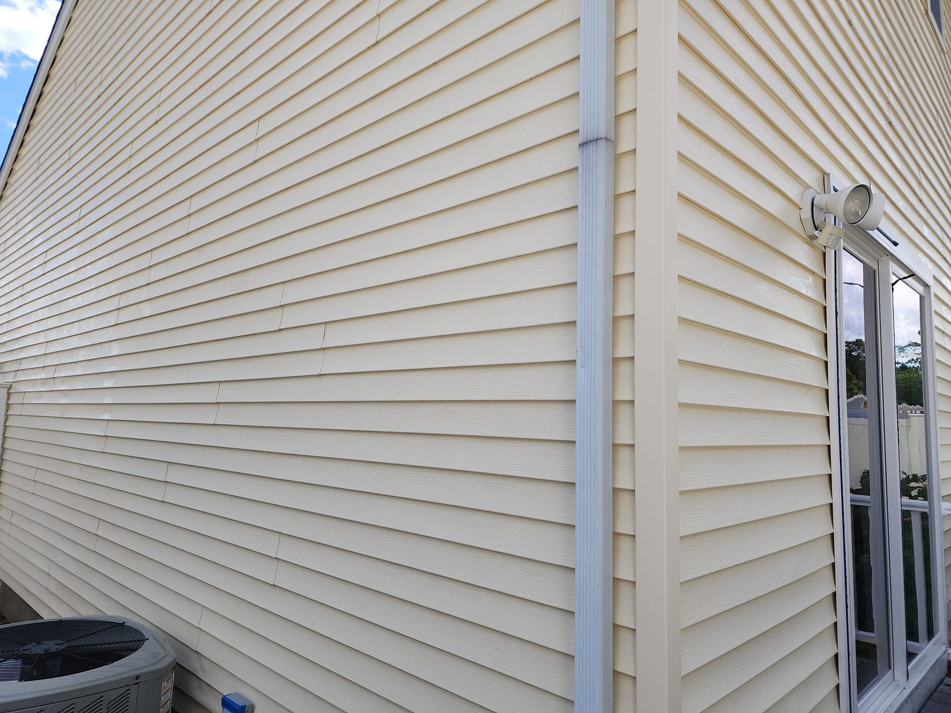 The side of a house with white siding after cleaning.