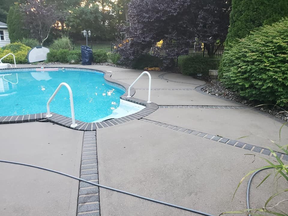 A large swimming pool is surrounded by a clean concrete patio.