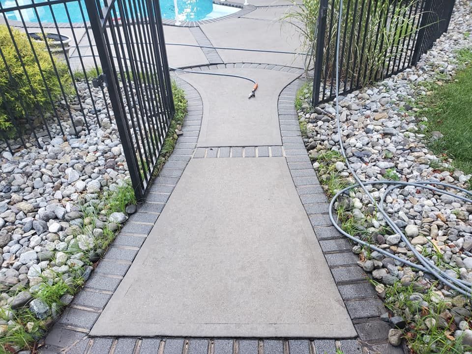 A after image of a walkway leading to a pool with a hose on the side of it.