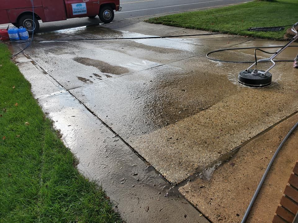 A person is cleaning a driveway with a pressure washer.