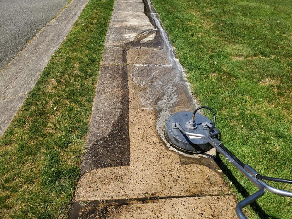 A person is cleaning a sidewalk with a machine.