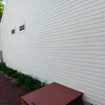 A large white house with a red trash can in front of it.
