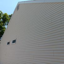 The side of a house with a lot of windows and a roof.