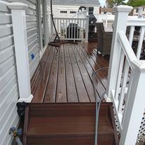 A wooden deck with stairs leading up to it and a white railing.