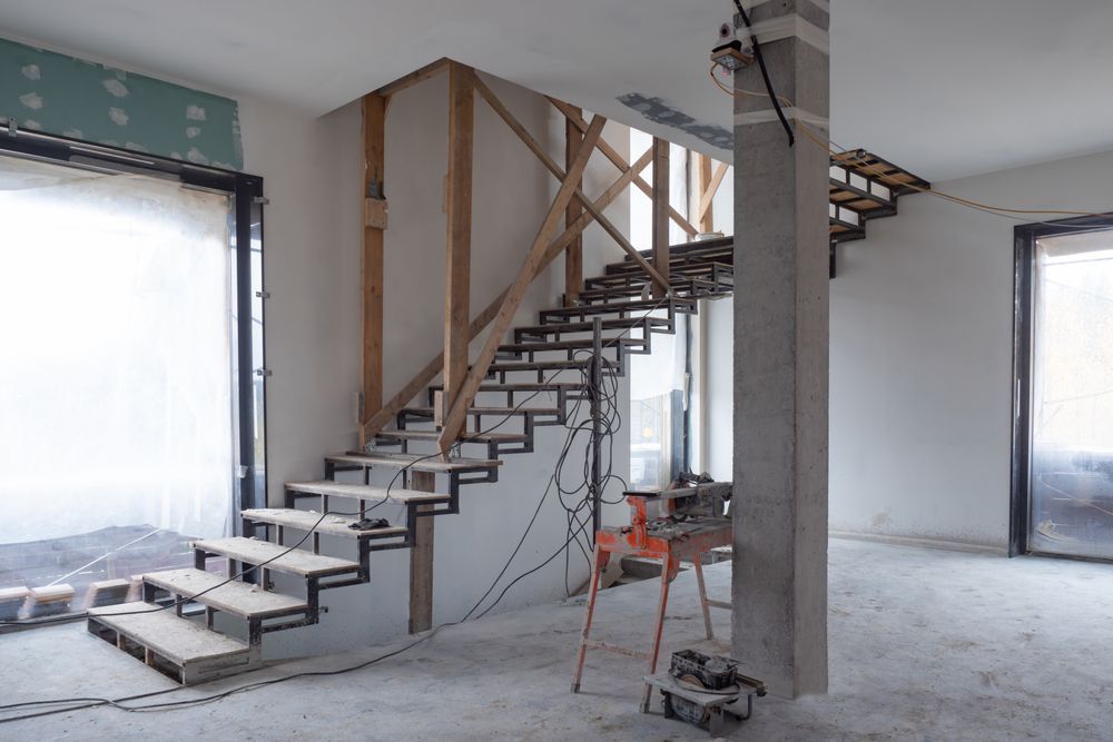 Staircase under construction. Metal treads, wooden framework, unfinished interior, tools on a red stand.