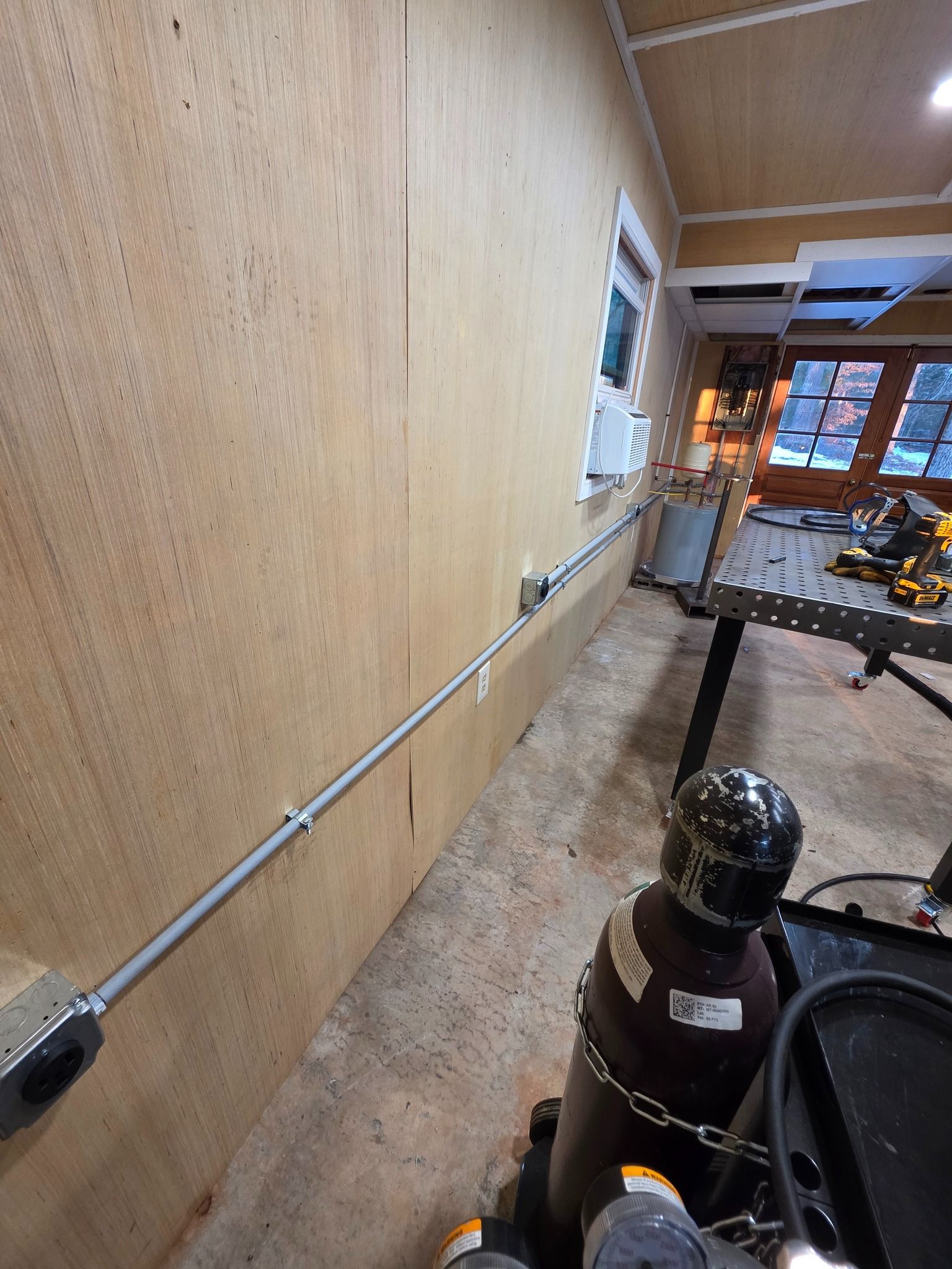 Woman in straw hat smiles, holding wine glass near a lake.