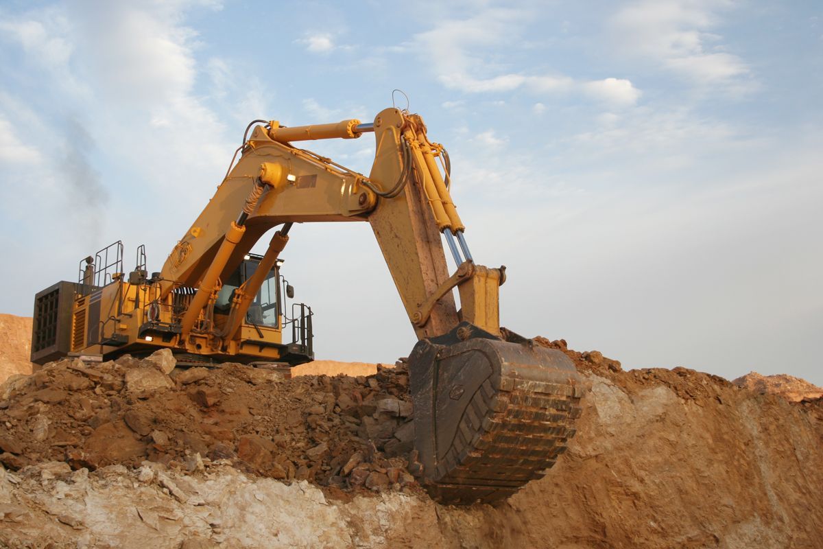 Excavator working under load during mining operations, with engine smoke visible from heavy digging.