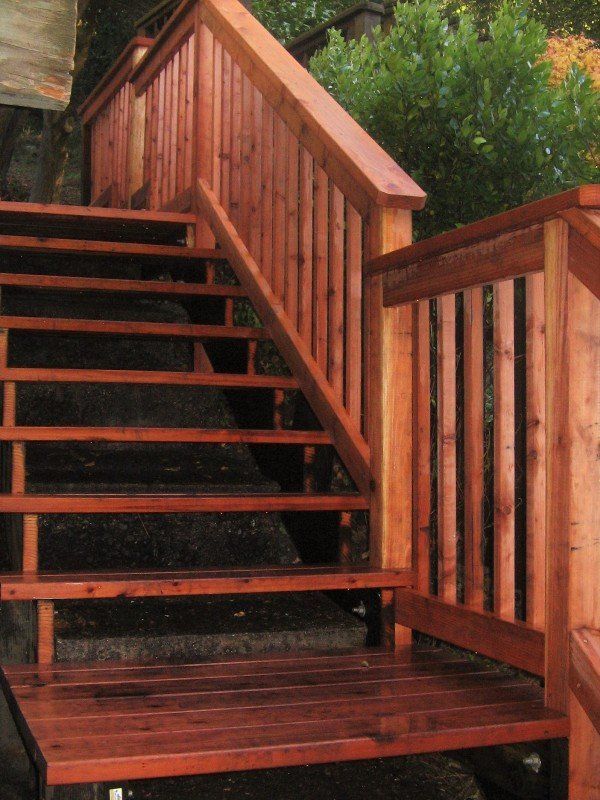 Wooden outdoor staircase with handrails, stained reddish-brown.
