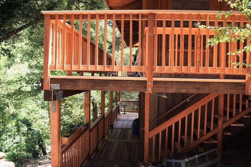 Wooden deck and railing system attached to a building, surrounded by trees.