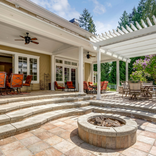 Stone patio with fire pit, covered seating, and a pergola.