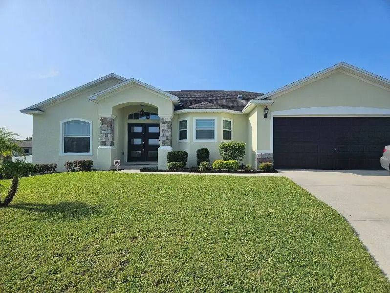 Light green house with a black garage door and green lawn.