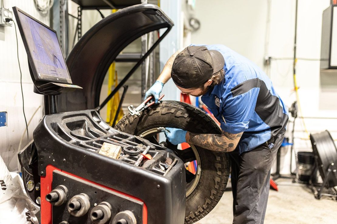 Expert Worker with Tire in Garage | Bruno Automotive