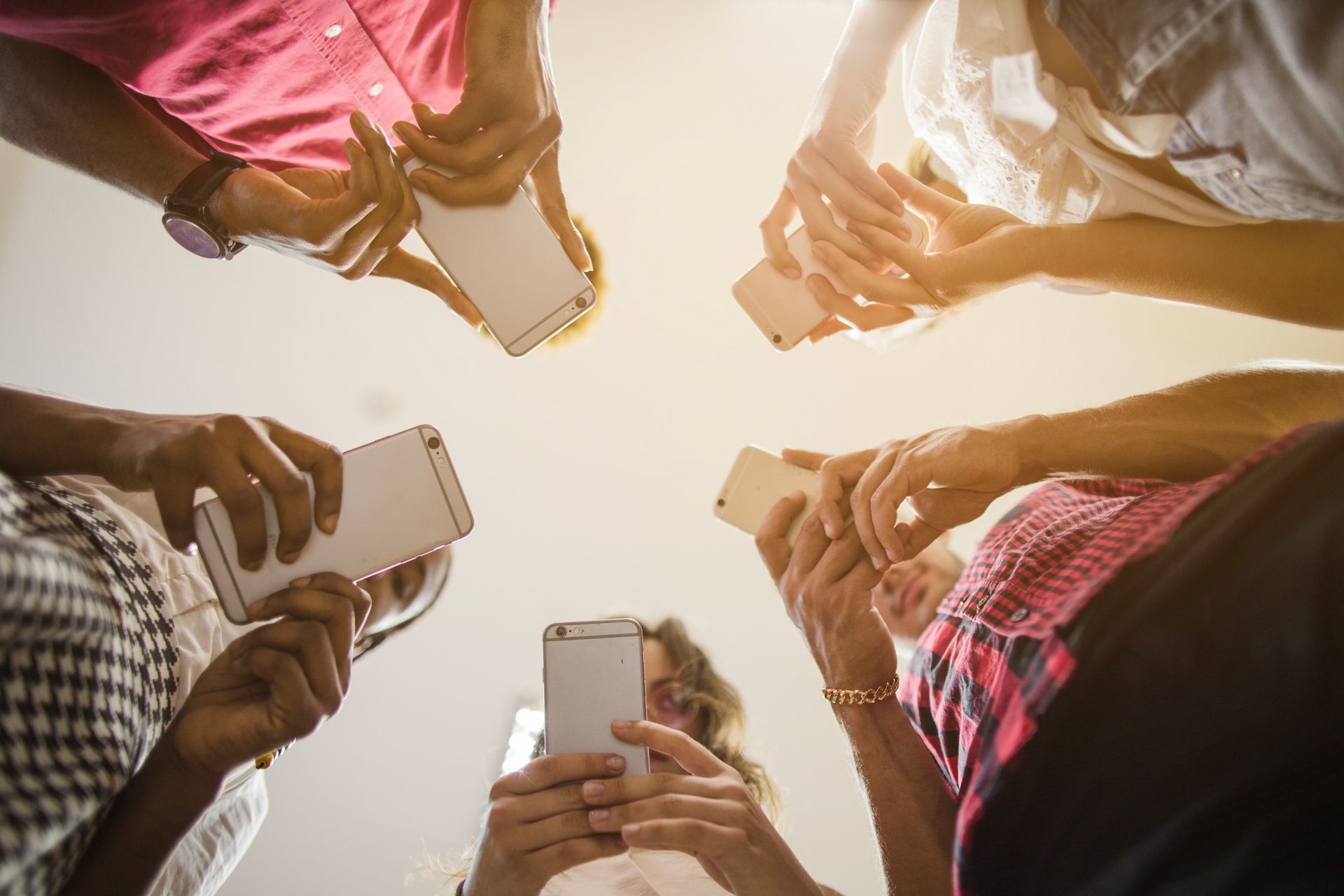 Um grupo de pessoas está em círculo olhando para seus celulares.