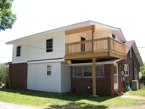 A white house with a wooden deck on top of it.