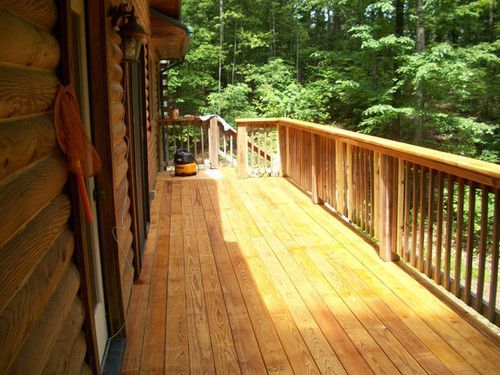 A wooden deck with a railing and trees in the background