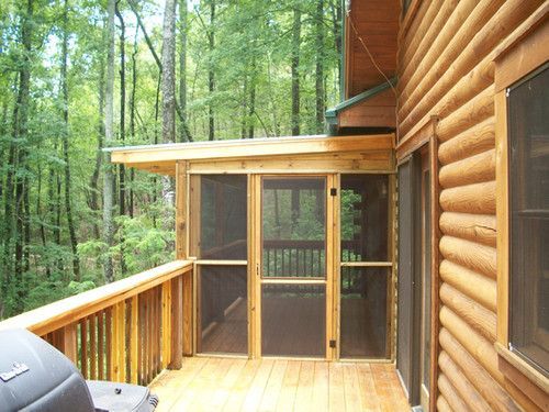 A screened in porch on the side of a log cabin