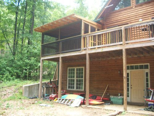 A log cabin with a large deck and kayaks on it