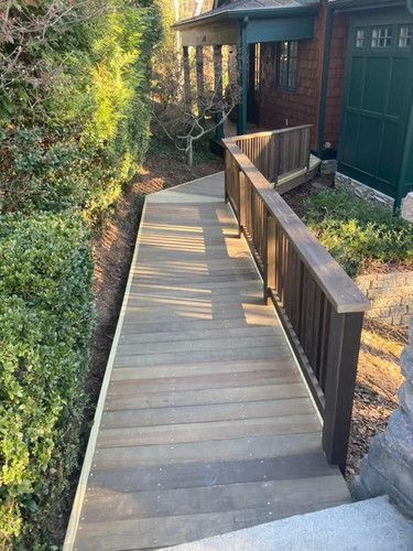 A wooden walkway with a railing leading to a house.