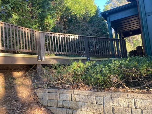 A wooden deck is sitting on top of a brick wall next to a house.