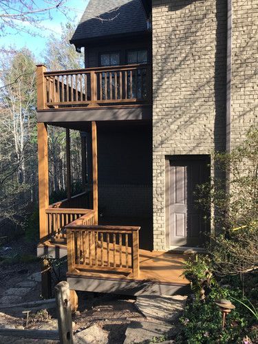 A brick house with a wooden deck and stairs leading up to it.
