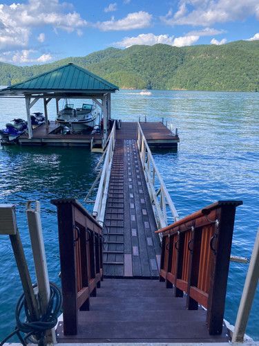 A dock with stairs leading up to a boathouse on a lake.