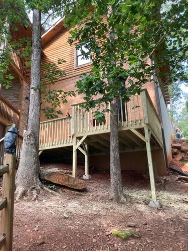 A house with a wooden deck surrounded by trees.