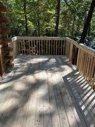 A wooden deck with a railing in the woods.