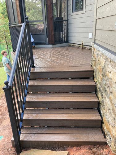 A man is standing on a deck with stairs and a railing.