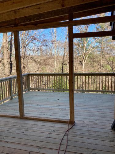 An empty wooden deck with a view of the woods.