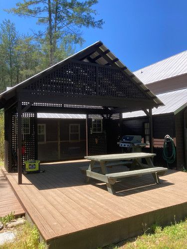 A wooden deck with a picnic table under a pergola.