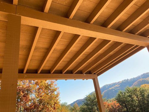 The ceiling of a wooden structure with mountains in the background.