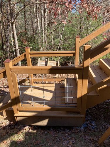 A wooden deck with stairs and a gate in the woods.