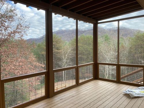 A screened in porch with a view of the mountains and trees.