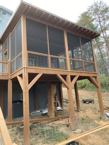 A screened in porch is being built on top of a wooden deck.
