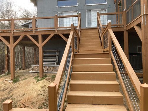 A wooden deck with stairs leading up to a house.
