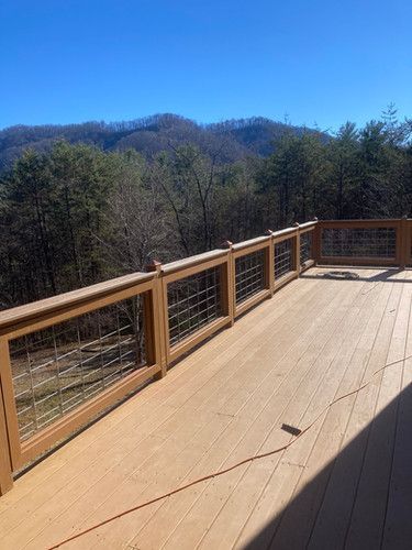 A large wooden deck with a fence and mountains in the background.