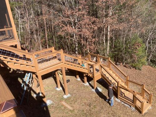 A man is standing on a wooden deck in the woods.