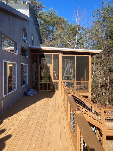A large house with a screened in porch and a wooden deck.