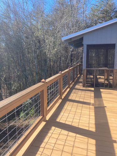 A wooden deck with a fence and a house in the background.