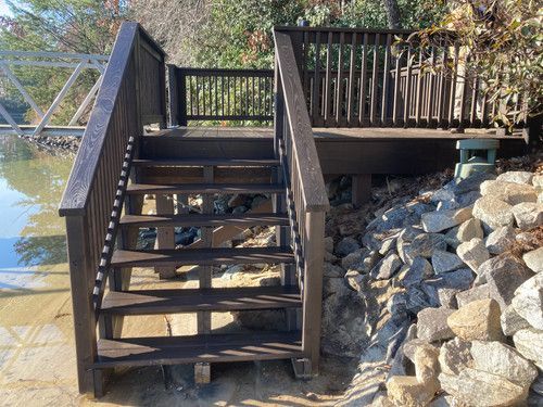 A wooden deck with stairs leading up to it next to a body of water.
