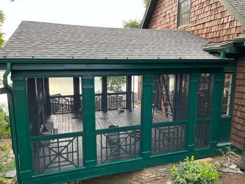 A screened in porch on the side of a house.